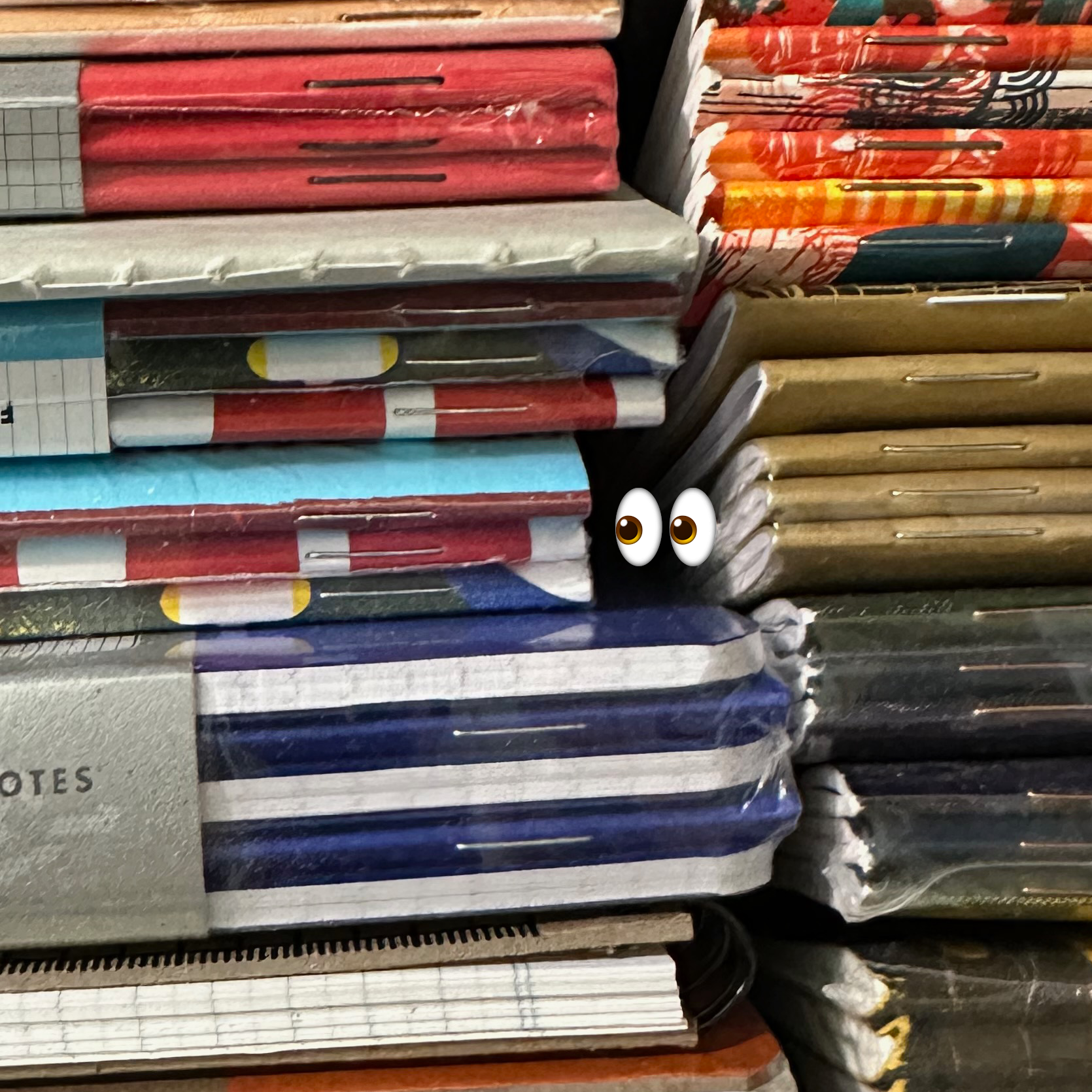 Stacks of Field Notes notebooks with eyeball emoji in center, looking left